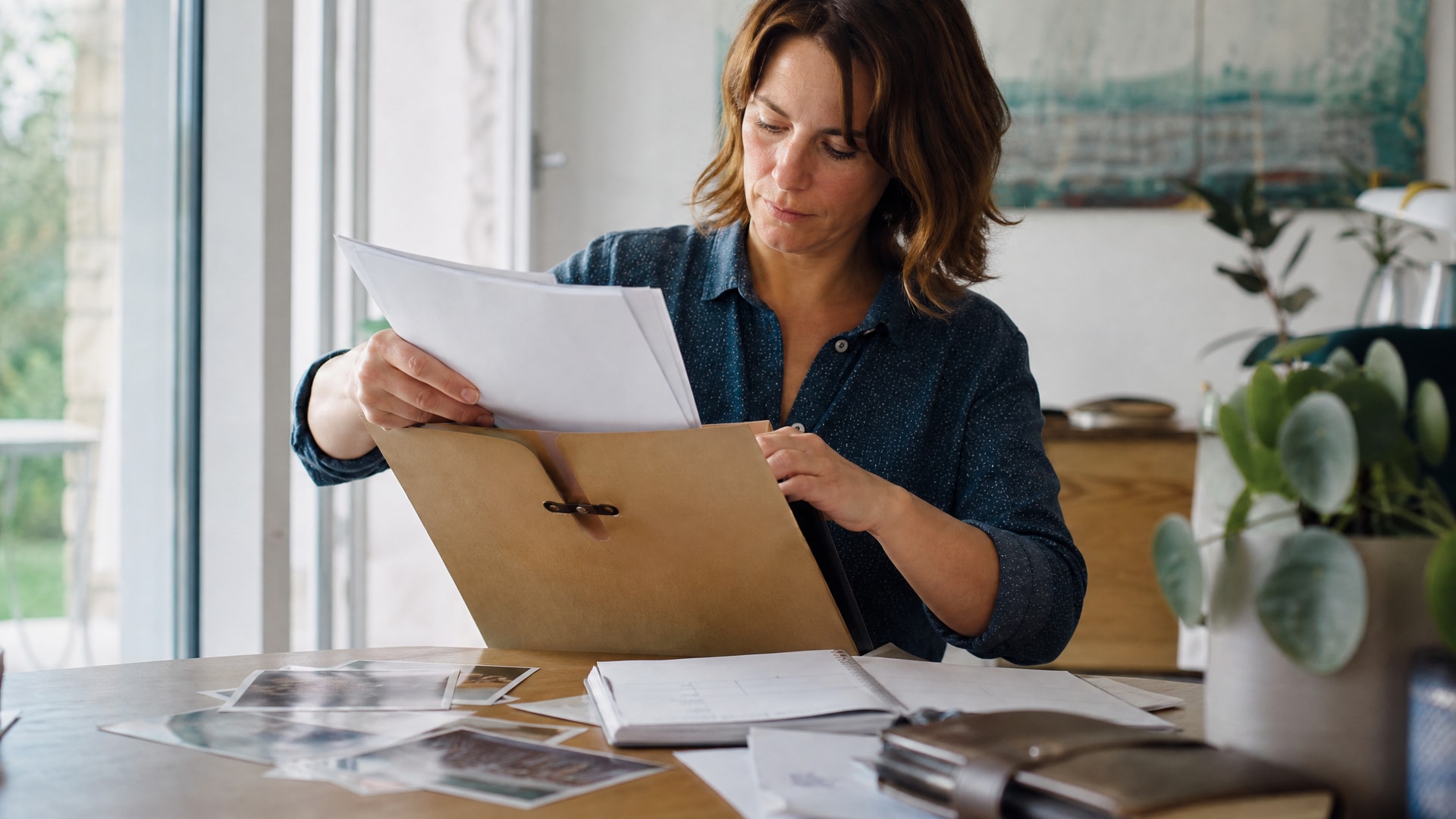 Business owner gathering printed evidence in a cardboard folder on her desk